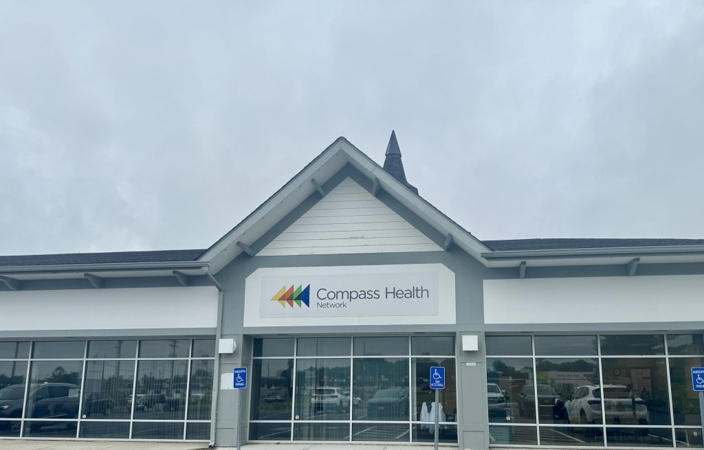Front of Compass Health Network building with a peaked roof and large glass storefront, sign visible above entrance